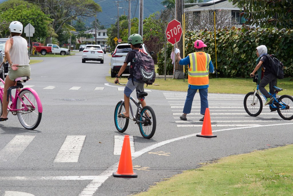 Elsie Miyashiro guards the intersection of 662 N. Kainalu Drive and Kaha Streets in Kailua. ItÕs a small but busy intersection behind Kainalu Elementary school.  Miyashiro was photographed on Thursday April 3rd during her afternoon shift. (David Croxford/Civil Beat/2025)