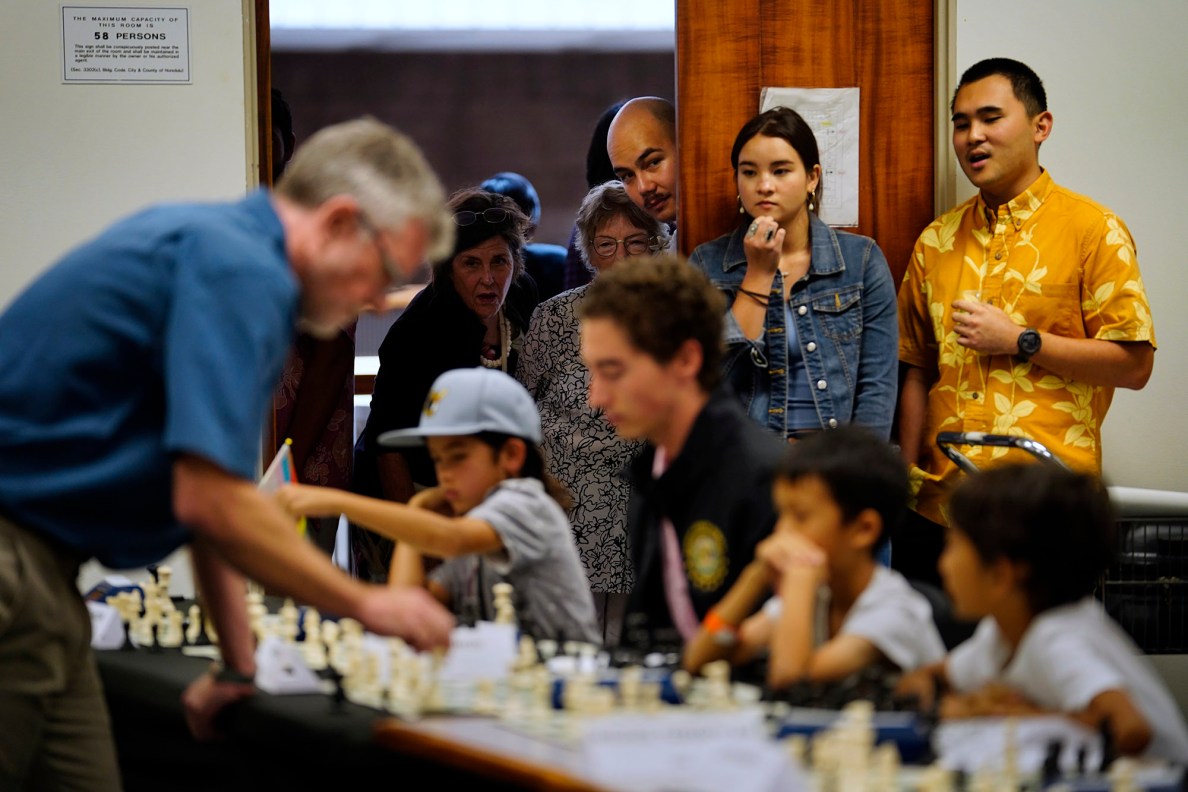 With the room full, spectators peer through an open door as National Master Cornelius Rubsamen simultaneously plays 20 people at the Art at the Capitol event Friday, April 11, 2025, in Honolulu. (Kevin Fujii/Civil Beat/2025)