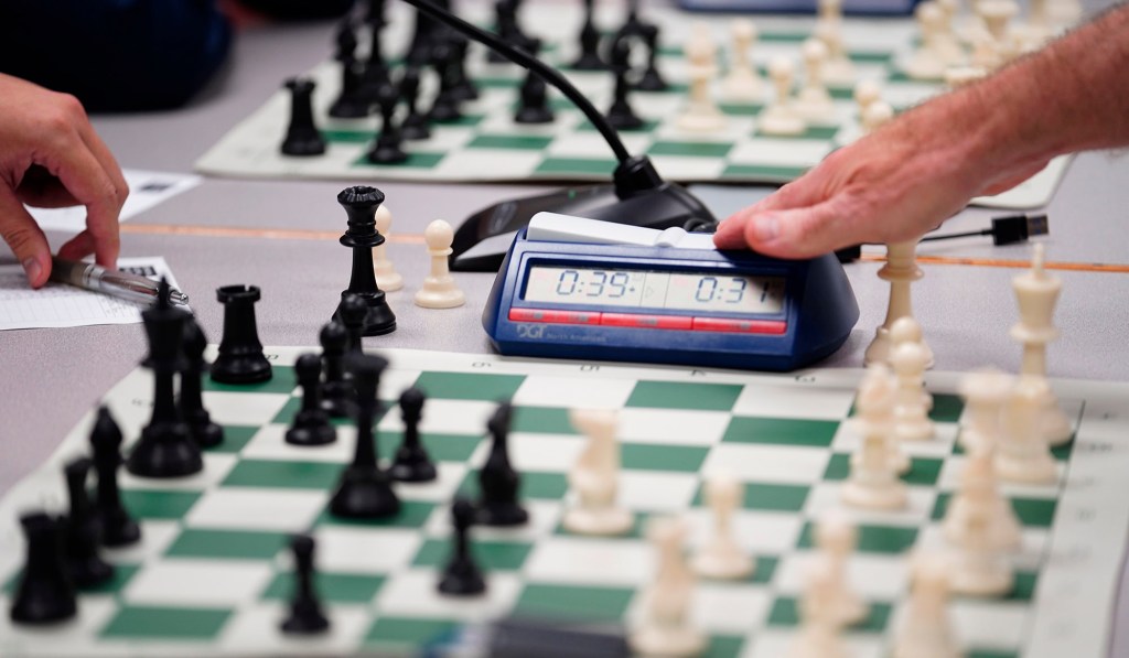 National Master Cornelius Rubsamen taps the chess clock after making his move in one match before moving to the next while simultaneously playing 20 people at the Art at the Capitol event Friday, April 11, 2025, in Honolulu. The theme for this year’s event is ‘Kālena, the Talent of Hawai‘i.’ (Kevin Fujii/Civil Beat/2025)