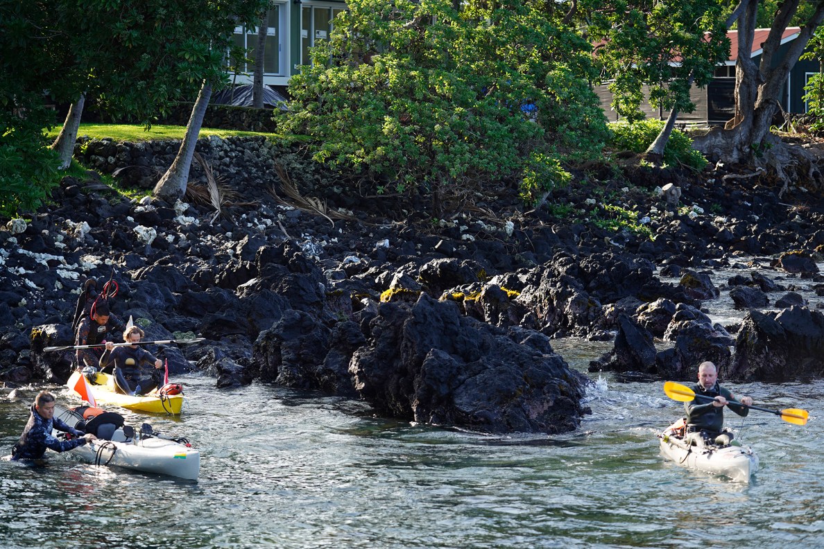 Spearfishermen launch their kayaks at Nāpoʻopo‘o Wharf to compete in the Kealakekua Bay Non-Native I‘a (fish) Removal Event Sunday, May 18, 2025, in Captain Cook. Spearfishing has been banned in the Marine Life Conservation District since 1969. Numerous groups worked with state and local agencies for a special permit to close the bay to other aquatic activities and tourism for the morning. (Kevin Fujii/Civil Beat/2025)