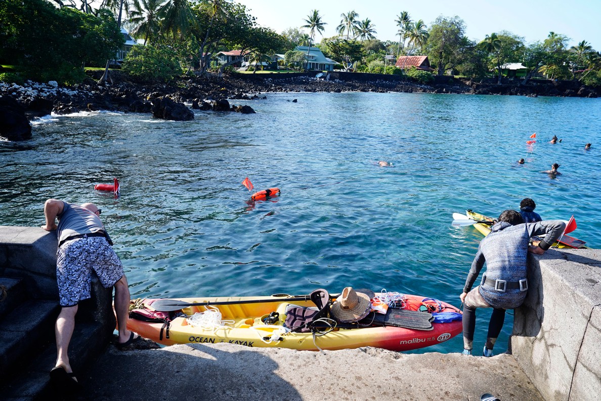A spear fisherman gets help lowering a kayak from Nāpoʻopoʻo Wharf during the Kealakekua Bay Non-Native I‘a (fish) Removal Event Sunday, May 18, 2025, in Captain Cook. Kona Boys was one of many sponsors who provided kayaks. (Kevin Fujii/Civil Beat/2025)