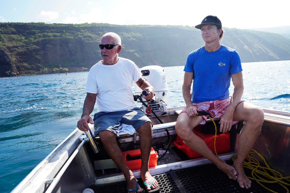 Charles Kealoha Leslie, better known as Uncle Chuck, steers around his life-long home water, with Bryce Groark, Moonjelly non-profit and Living Ocean Productions, during the Kealakekua Bay Non-Native I‘a (fish) Removal Event Sunday, May 18, 2025, in Captain Cook. (Kevin Fujii/Civil Beat/2025)