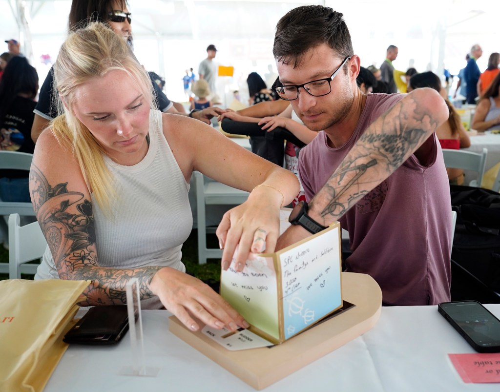Kalyn and Cameron Green assemble their lantern for the 27th Annual Shinnyo Lantern Floating Hawaiʻi Monday, May 26, 2025, at Ala Moana Regional Park in Honolulu. They’re remembering family and military friends. 6,000 lanterns with messages to lost loved ones are launched by family members. (Kevin Fujii/Civil Beat/2025)