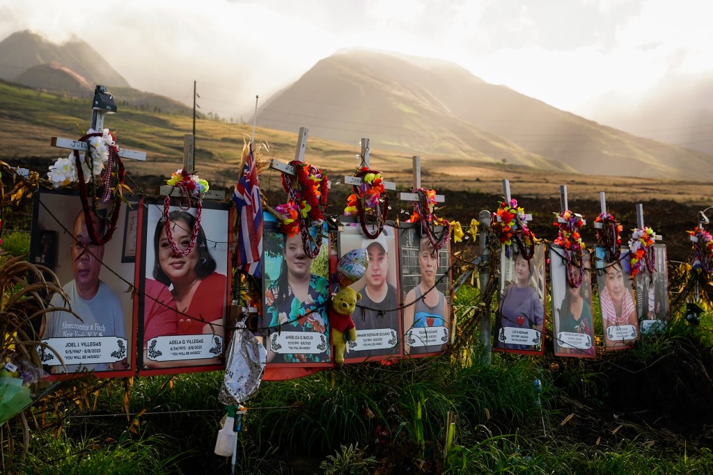 Photos of victims are seen placed under white crosses at a memorial for victims of the August wildfire above the Lahaina Bypass highway, Wednesday, Dec. 6, 2023, in Lahaina, Hawaii. The wildfire that tore through the heart of the Hawaii island of Maui this summer showed how older residents are at particular risk from disasters. Sixty of the 100 people killed in the Maui fire this summer were 65 or older. (AP Photo/Lindsey Wasson)