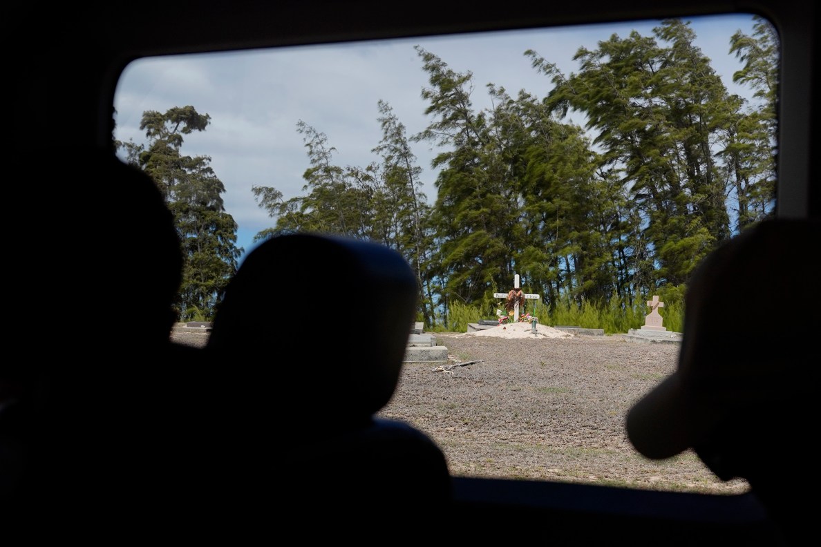 Kalaupapa Saints Tour passes a newer Papaloa Cemetery grave Thursday, Sept. 18, 2025, in Kalaupapa. Three Hansen’s Disease patients remain in Kalaupapa. Three more patients have moved off island. (Kevin Fujii/Civil Beat/2025)