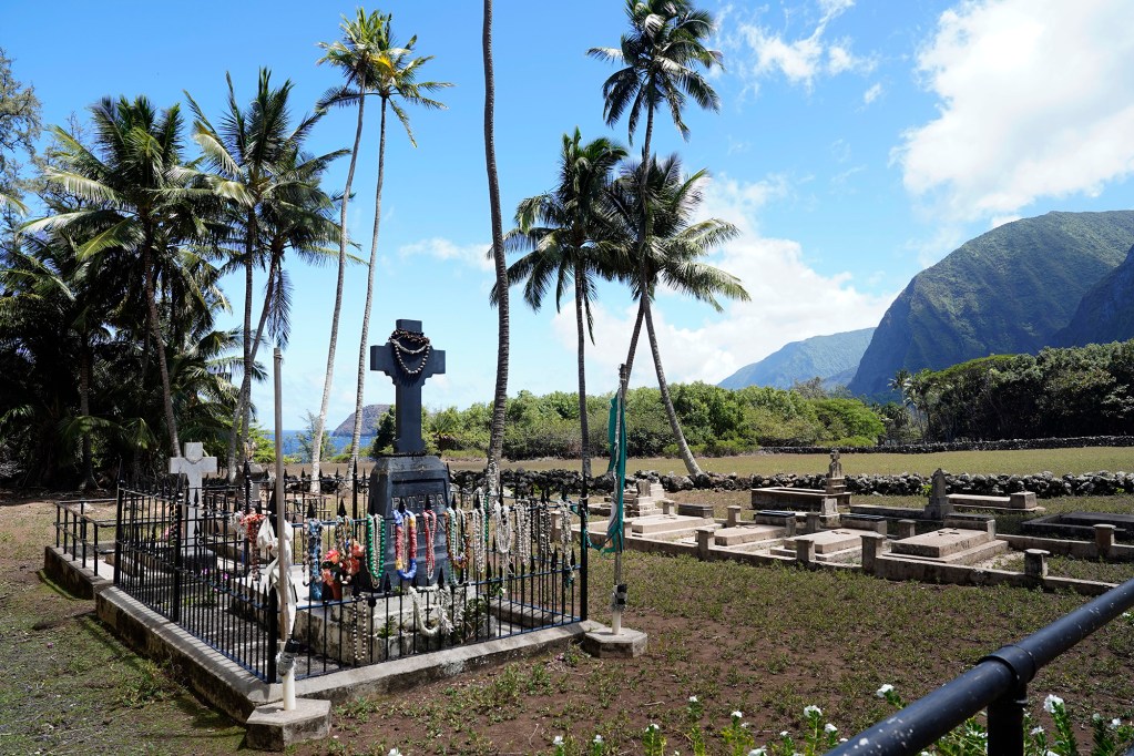Kalaupapa Saints Tour stops at Father Damien’s grave atSaint Philomena’s Church Thursday, Sept. 18, 2025, in Kalaupapa. Covid closed Kalaupapa National Historical Park five years ago. Multiple state and federal agencies coordinated to allow a patient-owned tour company to bring visitors back. (Kevin Fujii/Civil Beat/2025)