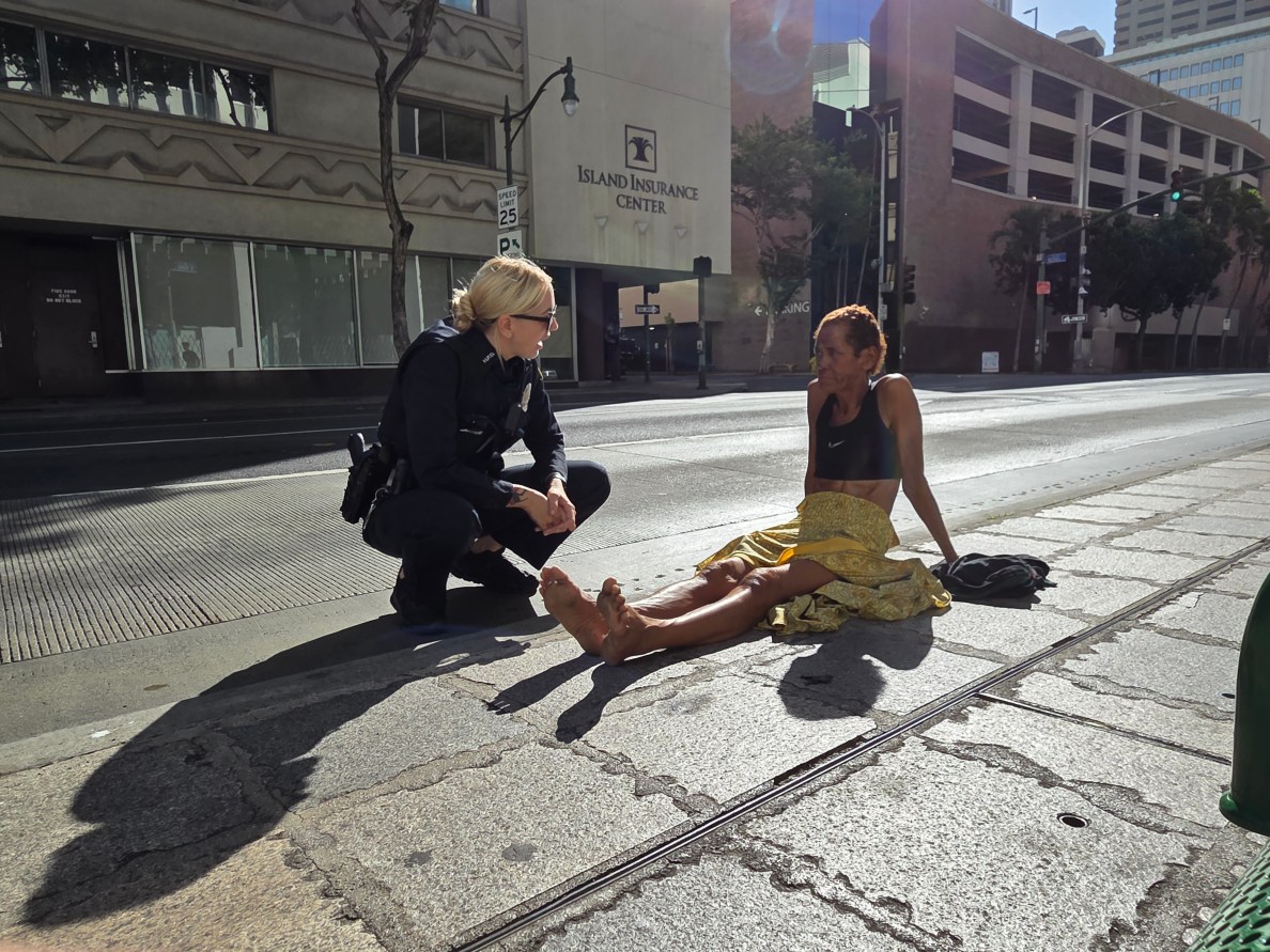 Honolulu Police Officer speaks with a woman named Helen before giving her a warning about violating Honolulu laws that prohibit sitting or lying on public sidewalks.