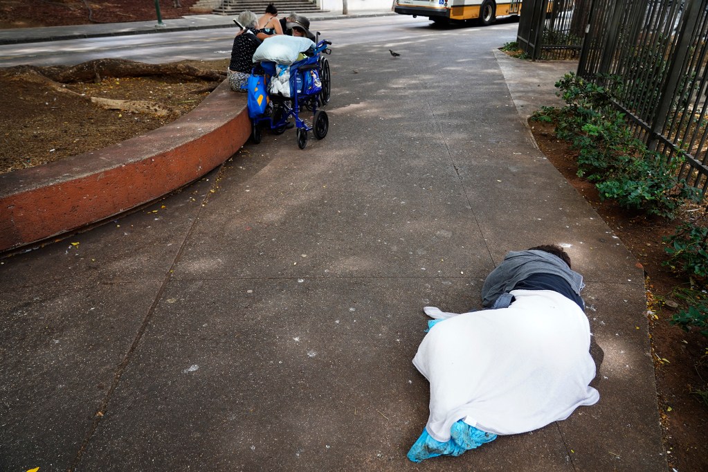 A homeless woman sleeps on a Chinatown sidewalk Tuesday, Nov. 4, 2025, in Honolulu. (Kevin Fujii/Civil Beat/2025)