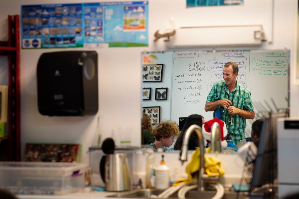 Hawaiʻi Technology Academy Kauaʻi teacher Drew Cohick talks with students during an advisory period Wednesday, Nov. 19, 2025, in a Līhuʻe office park. Cohick is reflected in a mirror mounted on a wall. (Kevin Fujii/Civil Beat/2025)