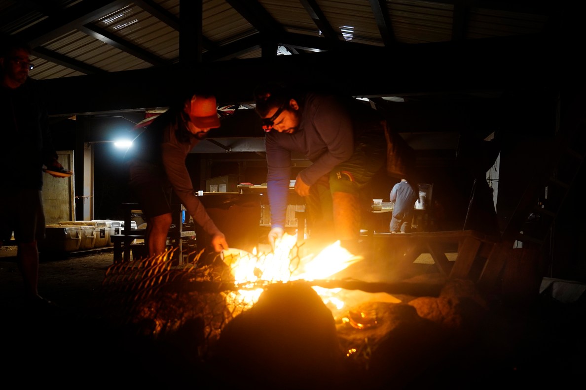 Protect Kahoʻolawe ʻOhana (PKO) Kawai Lu‘uwai, left, and Kaipu Keala burn paper rubbish after dinner Monday, Jan. 5, 2026, in Hakioawa. PKO celebrates the 50th year of sovereign land. (Kevin Fujii/Civil Beat/2026)
