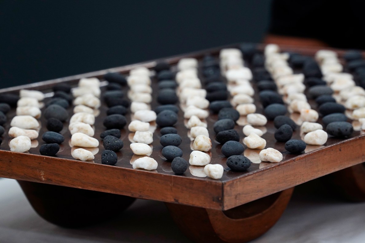 Kōnane game pieces are placed atop the kūpuna papamu Friday, Jan. 30, 2026, at the Bishop Museum in Honolulu. The black game pieces are basalt called 'ili'ili 'ele'ele. ‘Ili'ili ke'oke'o are the white coral game pieces. (Kevin Fujii/Civil Beat/2026)