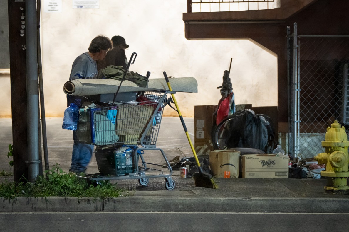 Two men next to a shopping cart at the corner of Vineyard and Liliha.