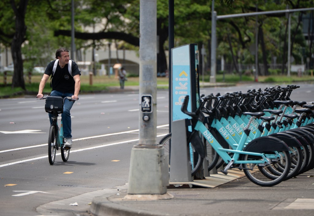 A bicyclist rides past a rack of Biki rental bicycles on South King Street April 20, 2026. (Craig Fujii/Civil Beat/2026)