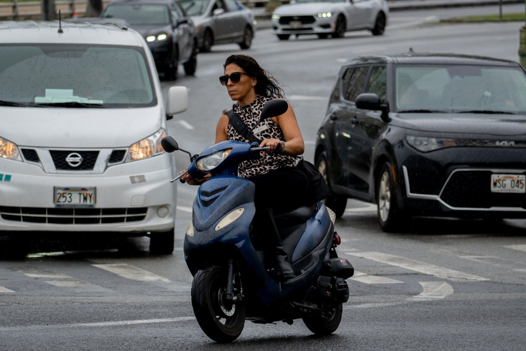 An unhelmeted moped rider on Kalakaua Avenue in Waikiki April 13, 2026. (Craig Fujii/Civil Beat/2026)