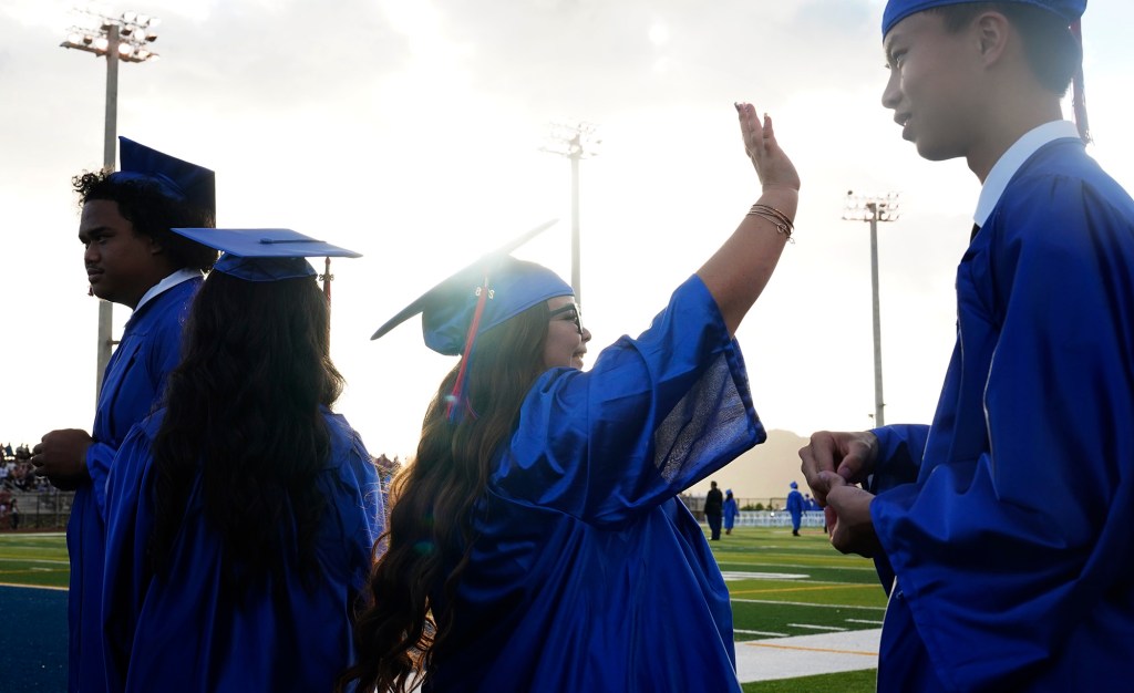 Waiʻanae High School senior Kawehi Windham waves to ʻohana and friends before the commencement ceremony Friday, May 22, 2026, in Waiʻanae. (Kevin Fujii/Civil Beat/2026)