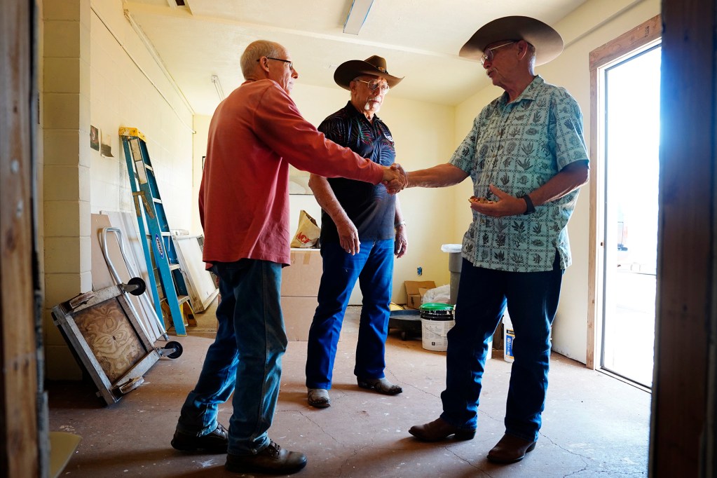Molokaʻi cattle ranchers Jack Spruance, left, shakes hands with Uncle Phillip “Mango” Stephens as Uncle Jimmy Ducauchelle looks on after talking story about dealing with the state’s imposed bovine tuberculosis quarantine Wednesday, May 27, 2026, in Kaunakakai. (Kevin Fujii/Civil Beat/2026)