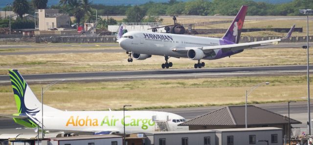 Hawaiian Airlines jet lands at Daniel Inouye Airport with foreground, Aloha Air Cargo.