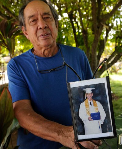 FILE - In this Monday, July 10, 2017 file photo, Clifford Kang, father of soldier Ikaika Kang, poses with a 2001 photo of his son in Kailua, Hawaii. Ikaika Kang is set to plead guilty Wednesday, Aug. 29, 2018, as charged in an indictment last year, defense attorney Birney Bervar said. He is agreeing to a 25-year sentence for charges that could have put him in prison for life. (Bruce Asato/Honolulu Star-Advertiser via AP, File)