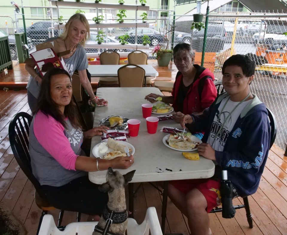 Volunteer Kay Inglis (back left) serves lunch to Lovely Reiner (front left), Troy Kuoha (back right) and Thomas Tadlas (front right) at the Wally House - St. Elizabeth’s Episcopal Church in Honolulu, HI, Tuesday, February 18, 2020.  Every Tuesday for the last two years food has been made available to those in need. (Ronen Zilberman photo Civil Beat)

