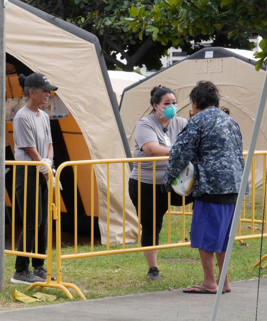 A city &amp; county worker helps by screening a homeless person before allowing him to enter the homeless tent compound set-up in the Old Stadium Park in Honolulu, HI, Saturday, March 28, 2020. (Ronen Zilberman photo Civil Beat)