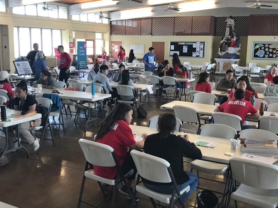 Volunteers and staff from Unite Here Local 5, The Legal Clinic and the UH Refugee & the Immigration Law Clinic help 
participants fill out naturalization applications at a free citizens assistance workshop at St. Theresa Cathedral in Honolulu. 