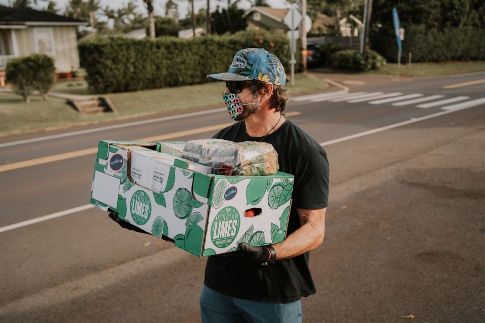 Campbell Farrell of Love the Sea on Maui carries a box of donations to eh food bank set up at the Kuau store.