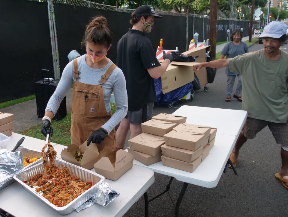 Nani Conklin and Nick Childs pass out meals to homeless and anyone else who is hungry on the street near Thomas Square Park in Honolulu, HI, on Sunday, June 14, 2020. The two volunteer with the local chapter of Food Not Bombs, a non-profit that has been serving meals made from donated food every Sunday since 2008. (Ronen Zilberman photo Civil Beat)