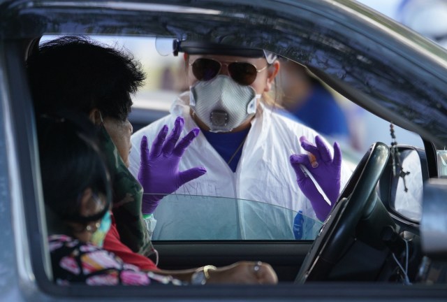 Premier Medical Group Hawaii team member esplain the swabbing process before performing a COVID-19 PCR swab test at Kakaako Waterfront Park parking lot. August 23, 2020