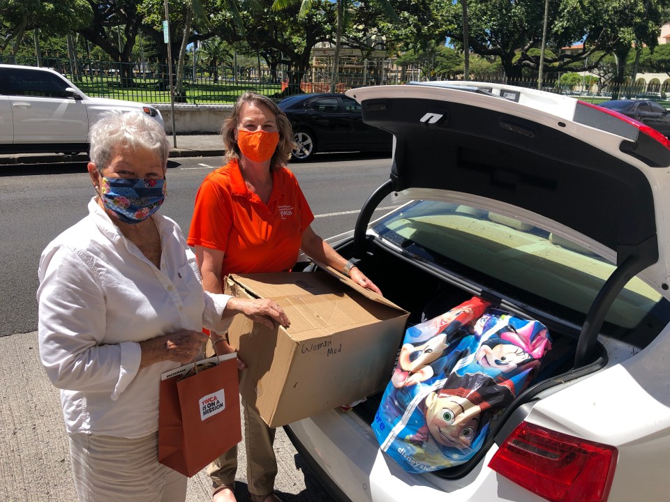 Dana Anderson of the Residential Youth Services and Empowerment picks up clothing donations provided by YWCA Oahu and YMCA of Honolulu. YWCA staffer Maryann Bray helps load the car.