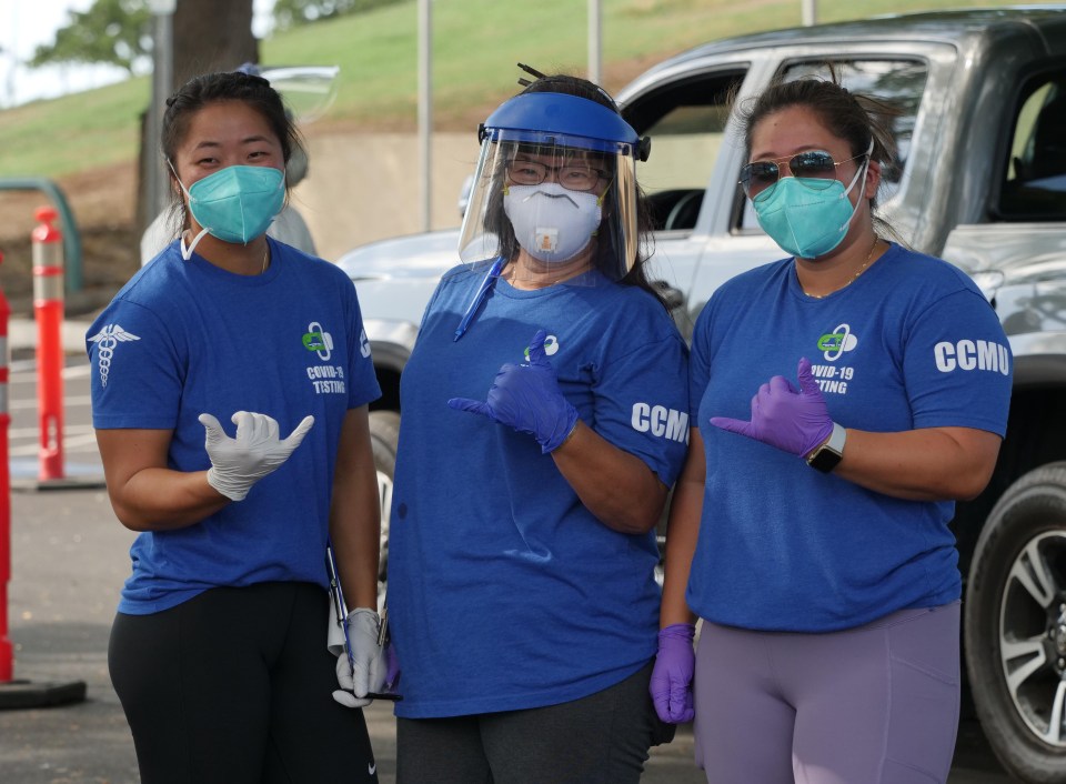 Celeste Horita (center) volunteers to help her daughters Chelsea Horita (left) and Cherise Horita (right) as they work with the COVID Command Mobile Unit during a drive-thru event held in Kaka'ako Sunday, August 23, 2020. (Ronen Zilberman photo Civil Beat)