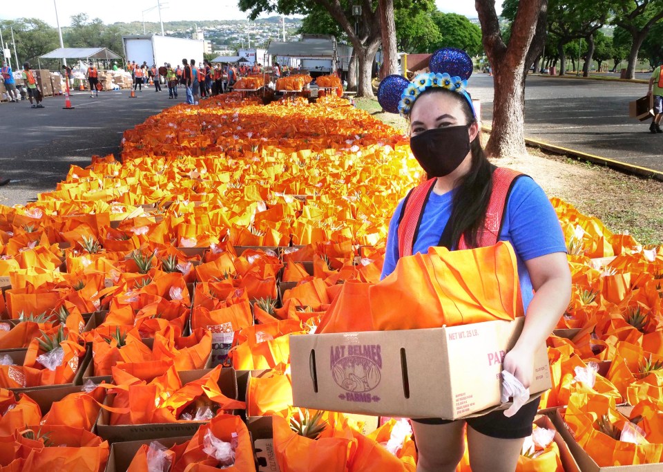Volunteer Crystal Siruno holds a box of bagged food to be distributed to 2500 Hawai'i residents arriving to Aloha Stadium Monday, November 16, 2020. Crystal said she wore her speical Mickey Mouse ears headband to "help spread a little magic" around the free pop-up food distribution event orgnanized by the Hawai'i Foodbank.