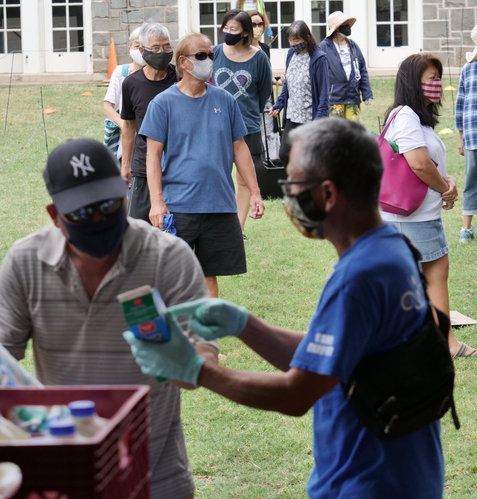 A volunteer from the Central Union Church passes out food to residents in line during a distribution event on their church grounds in Honolulu, Wednesday, December 9, 2020. (Ronen Zilberman photo Civil Beat)