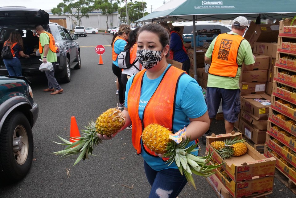 Hawai'i Foodbank volunteer, Natane Thompson, carries pineapples to load into waiting cars during a pop-up food distribution event at Kahihi District Park on Wednesday, December 9, 2020. (Ronen Zilberman photo Civil Beat)