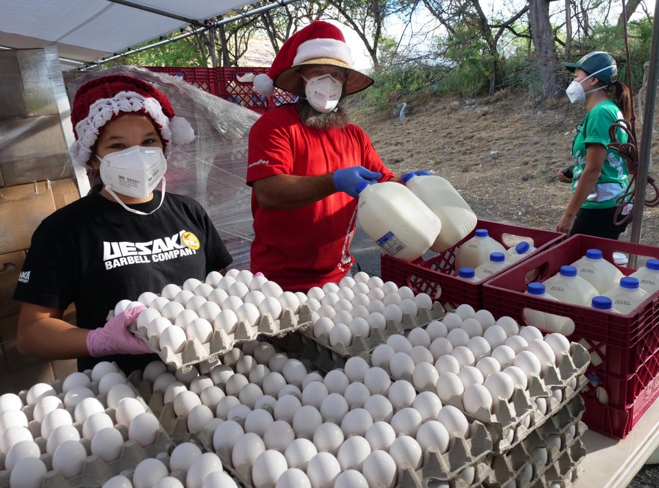 Jonathan Bailor, right, and his daughter Alexis Bailor dress for the Christmas spirit while volunteering to help load cars with food donations at the Waianae Coast Comprehensive Health Center during the pandemic in 2020.