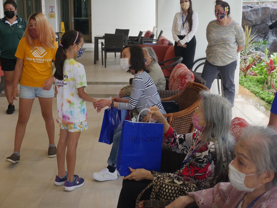 Children from the Boys &amp; Girls Club of Hawaii give presents of donuts and origami to Kupuna residents at the Kalakaua Gardens senior living community in Honolulu, Wednesday, July 21, 2021. The gifts were given in appreciation to kupuna who created and donated xeriscape dish gardens to the children to use for fundraising efforts in support of programming for the Boys &amp; Girls club.  In addition, materials for the creative garden dishes were made possible by donations from the Hawaii Potters Guild and the Cactus and Succulent Society of Hawaii.  (Ronen Zilberman photo Civil Beat)