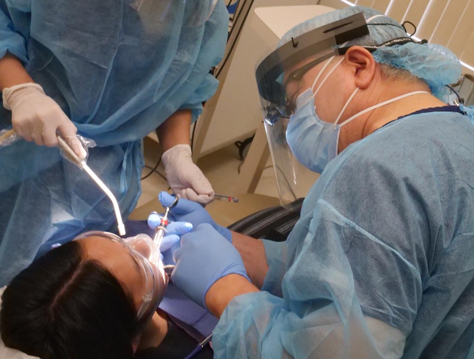 Dr. Craig Yamamoto begins a wisdom teeth extraction for Mackenzie Ayu, as part of the Oral Surgeons of Hawaii's first-ever Wisdom For Wisdom program, in Honolulu, Friday, July 23, 2021. The program offers wisdom teeth extraction for college-bound youth struggling to cover the costs of higher education. Participating dental surgeons like Dr. Yamamoto and others in his office, offer their services as a way to help and give back to their communities. Mackenzie says she feels lucky for this opportunity to take care of her dental needs without putting additional finiancial burden on her parents who have been economically affected by COVID-19.   (Ronen Zilberman photo Civil Beat)