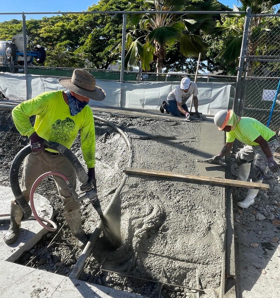Workers lay concrete to build new ramps, as part of a community-led improvement project to upgrade the skate park at Kailua District Park, on Monday, August 9, 2021. The project is being funded and spearheaded by the Association of Skateboarders in Hawai‘i (ASH), who are donating the design, materials, and construction of the skate park upgrades at a cost of nearly $130,000. (Ronen Zilberman photo Civil Beat)