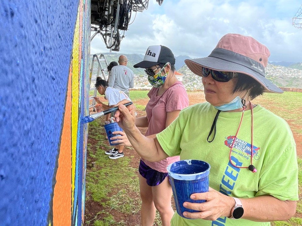 Roberta Leung (right) and her daughter Robbie Ann Leung volunteer to help paint a mural to beautify a cell phone tower at the Pu'u O Kaimuki Mini Park  in Kaimuki, Thursday, September 16, 2021. The mural project was a collaboration by artist Solomon Enos and the 808 Cleanups team as well as additional volunteers from around the neighborhood who joined in to help with the painting. (Ronen Zilberman photo Civil Beat)
