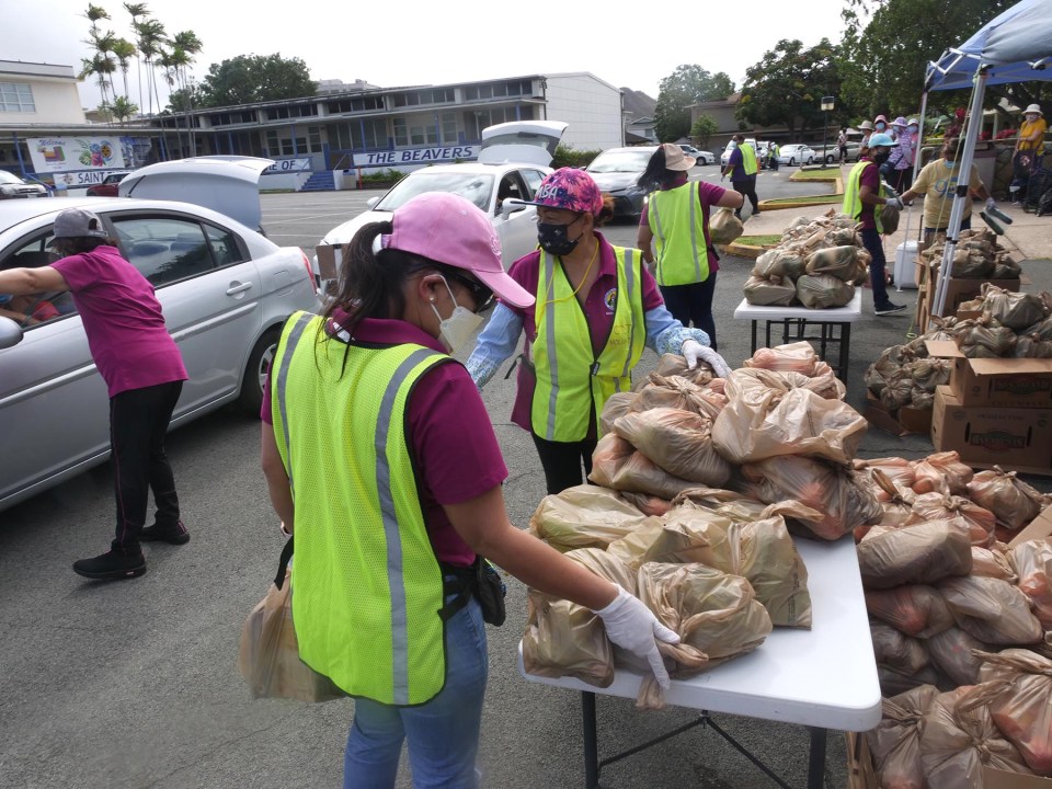Volunteers from the Co-Cathedral of St. Theresa Church load 250 bags of food into the car trunks of community members in need, during their pop-up food distribution event in Kalihi last fall.