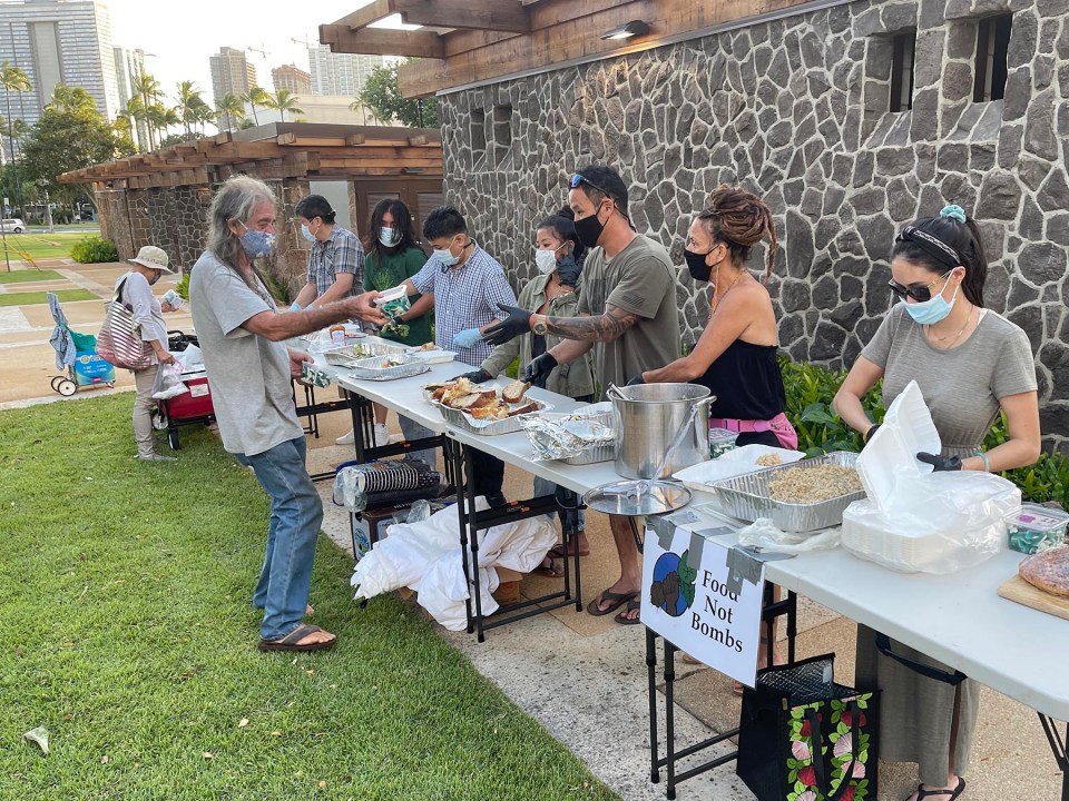 Volunteers from Food Not Bombs Honolulu provide free hot vegetarian meals free of charge to the public at Thomas Square Park on Sunday, October 10, 2021. The group provides free meals and hygenic supplies at the same location every week. (Ronen Zilberman photo Civil Beat)