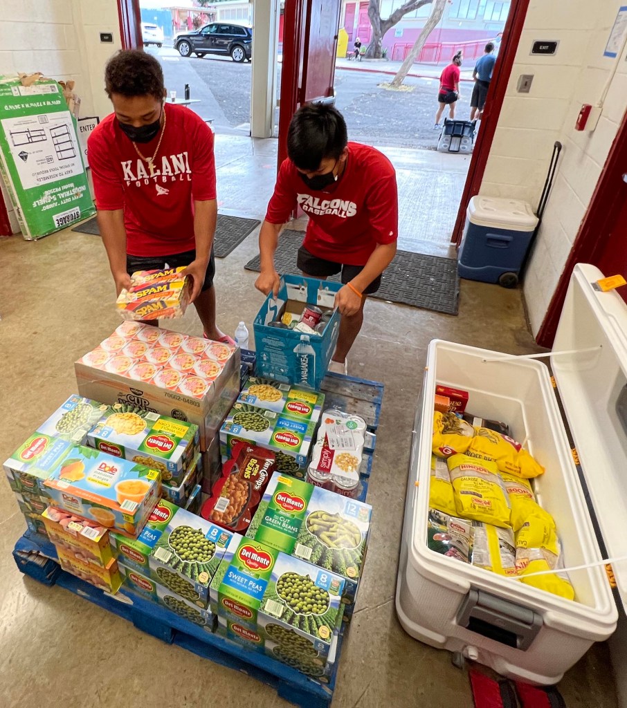 ChainTonsaldber (left) and Rex Nakamura, Sophmores at Kalani High School in Kahala, stack food donations onto palettes to be transferred to the Hawaii Food Bank, during their Drive Thru Thanksgiving Food Drive on Saturday, November 20, 2021. (Ronen Zilberman photo Civil Beat)