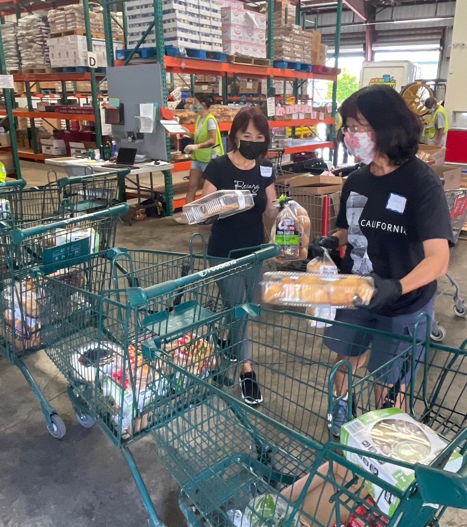 Rose Chu of Rotary downtown (left) and her friend Cheryl Lau volunteer to pack carts of food orders from clients, on the The Pantry website, Tuesday, November 2, 2021. Rotary District 5000 has commited to organizing volunteers on a weekly basis to help keep operations at The Pantry running smoothly. The Pantry provides nutritional food to qualifying individuals within Oahu communities through their online grocery-store style set-up. (Ronen Zilberman photo Civil Beat)