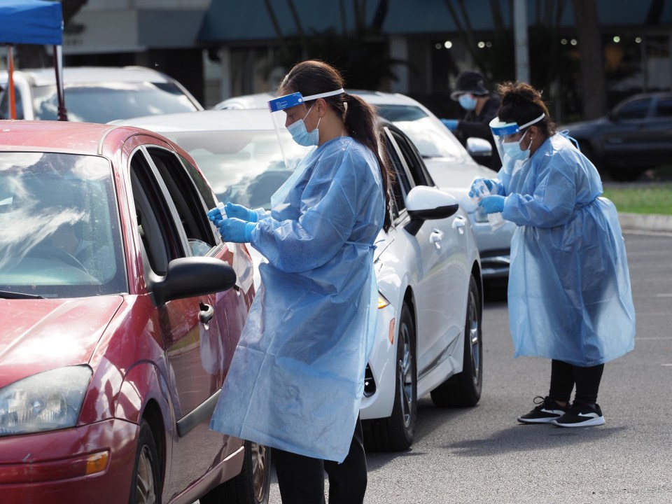 Medical technicians collect COVID-19 nose swab samples from people lined up in their cars, around the block, at the Blaisdell drive-through testing site in Honolulu, Monday, December 27, 2021. (Ronen Zilberman photo Civil Beat)