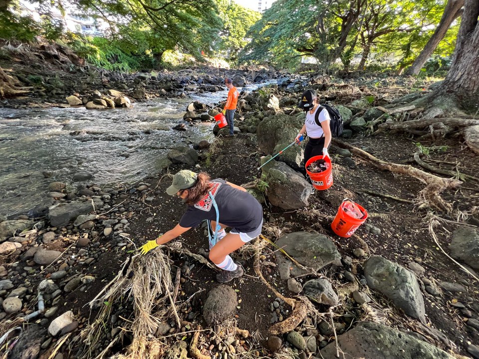 Anna Kasagawa (left), her sister Lihau Keliikuli-Peters (center), and Shane Baker volunteer with 808 Cleanups to remove trash from the Nu'uanu Stream in the Liliuokalani Park, Honolulu, Saturday, December 18, 2021.  Lihau chose to celebrate her birthday today by participating in the stream cleaning with 808 Cleanups. (Ronen Zilberman photo Civil Beat)