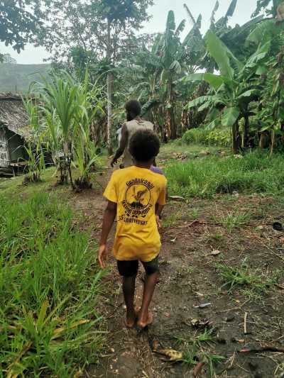 A young relative of the Manele family walks down a path behind John Manele Jr, the eldest son of his namesake and father, from the Manele's home to the road.