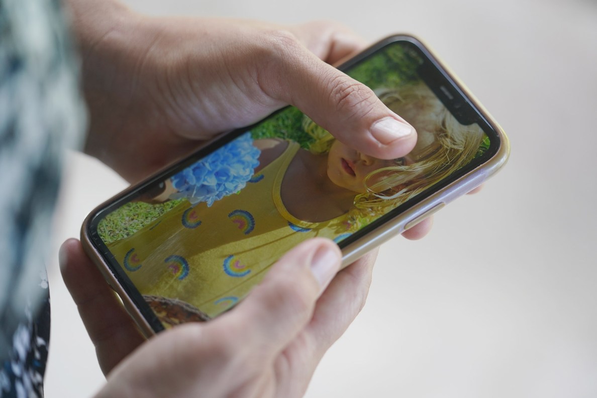 Sarah Coultas holds her phone with a photograph her daughter.