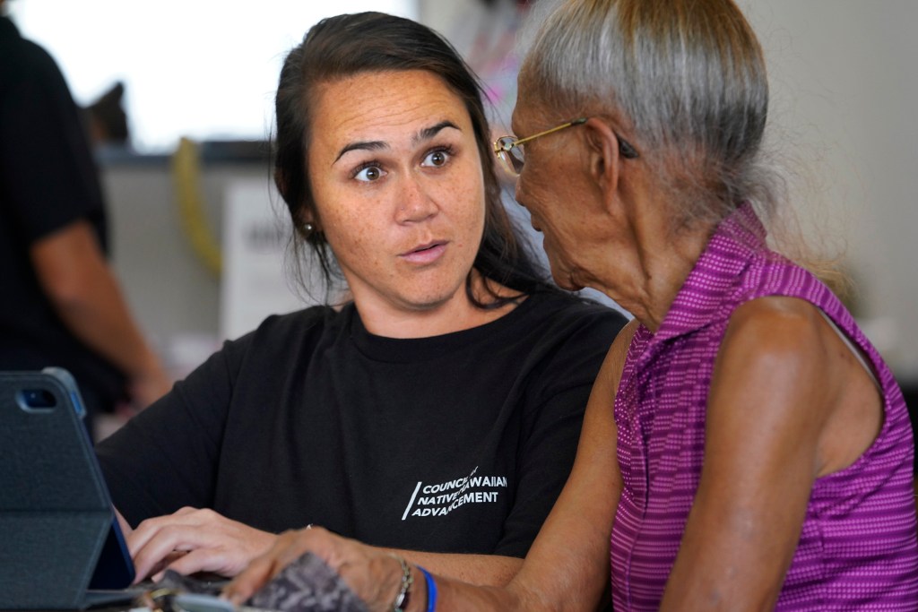 Kukui Keahi, left, registers June Shipe for fire assistance in Kahului. Smaller aid stations offered a less intimidating atmosphere and were part of an effort to make sure aid reached underserved communities from Lahaina. (Kevin Fujii/Civil Beat/2023)