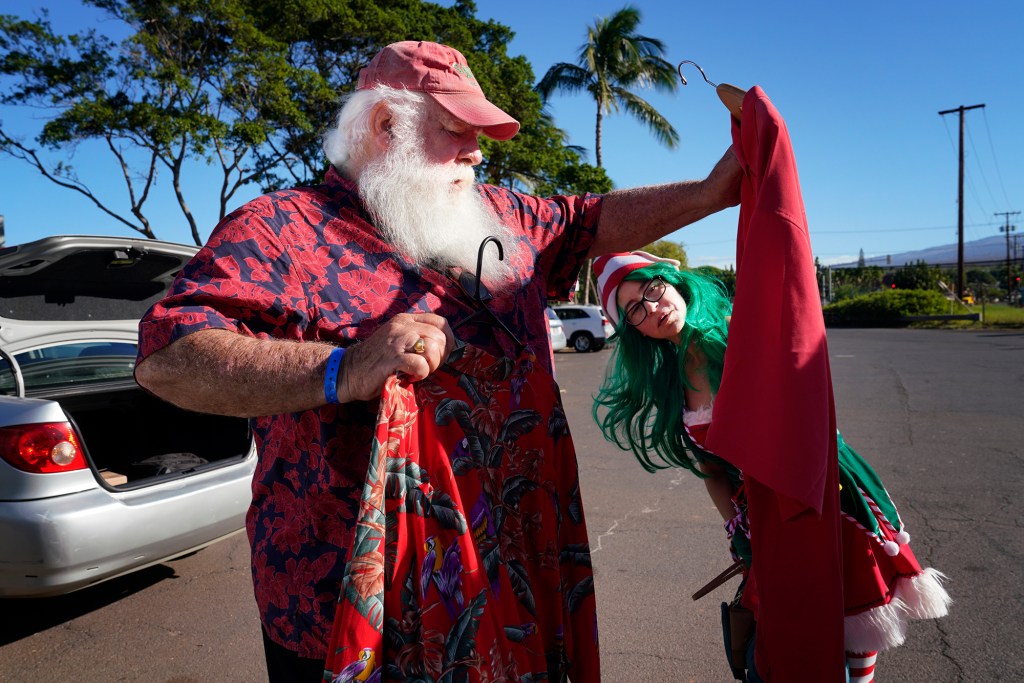Ron Proctor and Adelle Lennox pick a Christmas aloha shirt for the Santa Parade on Black Friday, Nov. 24, 2023, in Kihei. Proctor has played Santa for more than 25 years. The Aug. 8 fire destroyed his Lahaina home and belongings, including the hand-made Santa suit his daughter made. Lennox plays an elf today. Her Dazzle Entertainment company represents Proctor. (Kevin Fujii/Civil Beat/2023)
