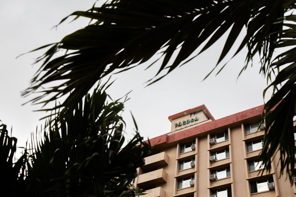 View of the Pagoda Hotel in Honolulu framed by palm trees.