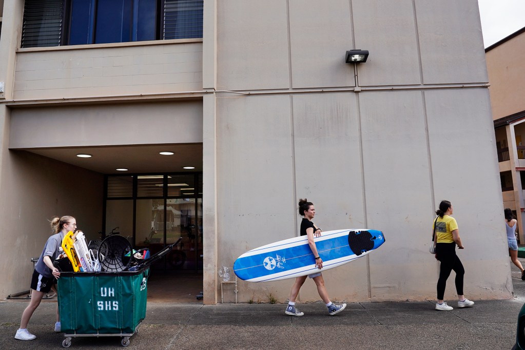 Resident Assistant Shannon Pederson, left, and Gina Trent, center of Walnut Creek, California, help move Trent’s younger sister into Hale Wainani student housing on the University of Hawaii Manoa campus Friday, Aug. 23, 2024, in Honolulu. The dorms were a buzz of activity on the last official day to move in before the semester begins next week. (Kevin Fujii/Civil Beat/2024)